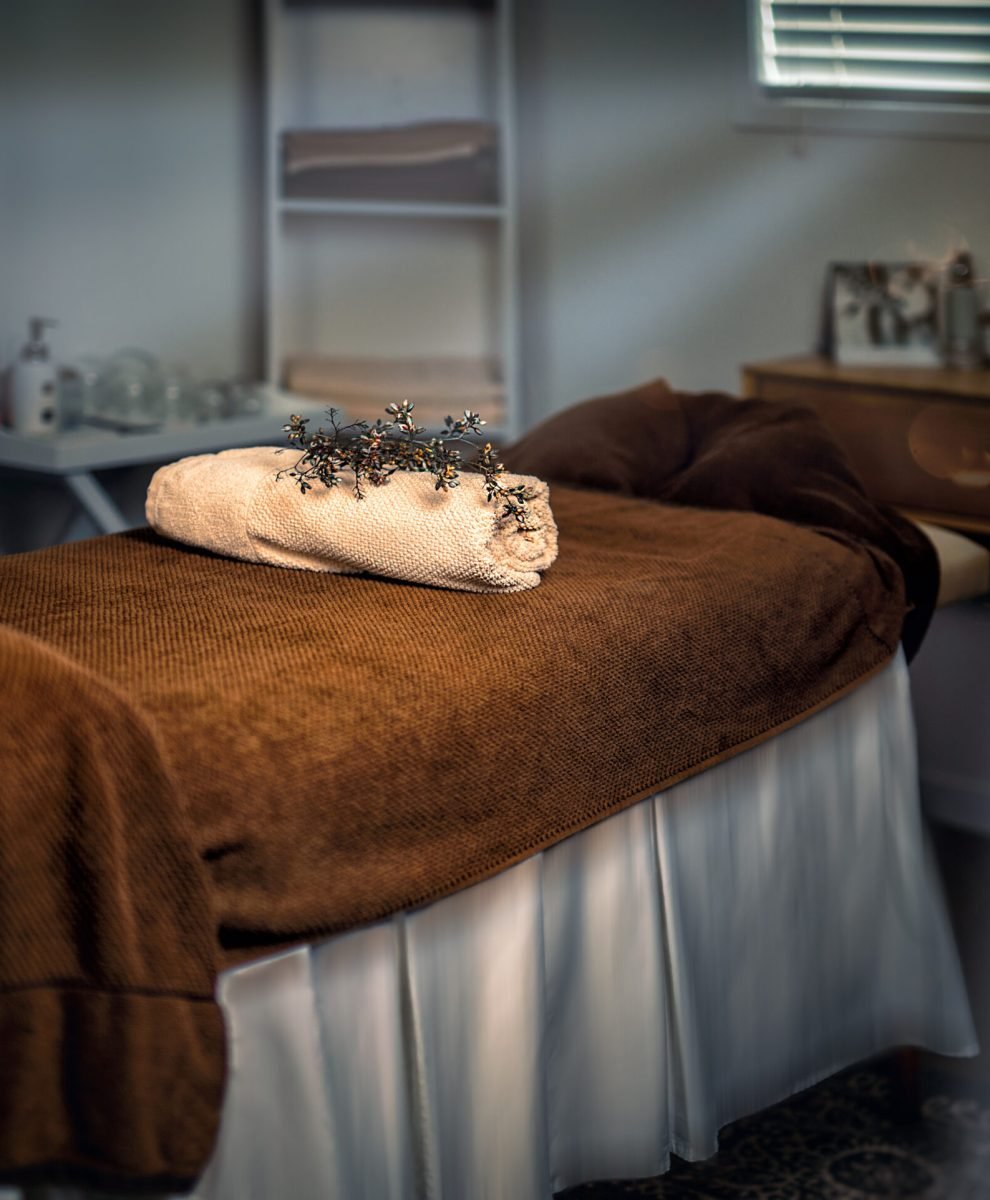 Massage table with towels and candle in a cabinet